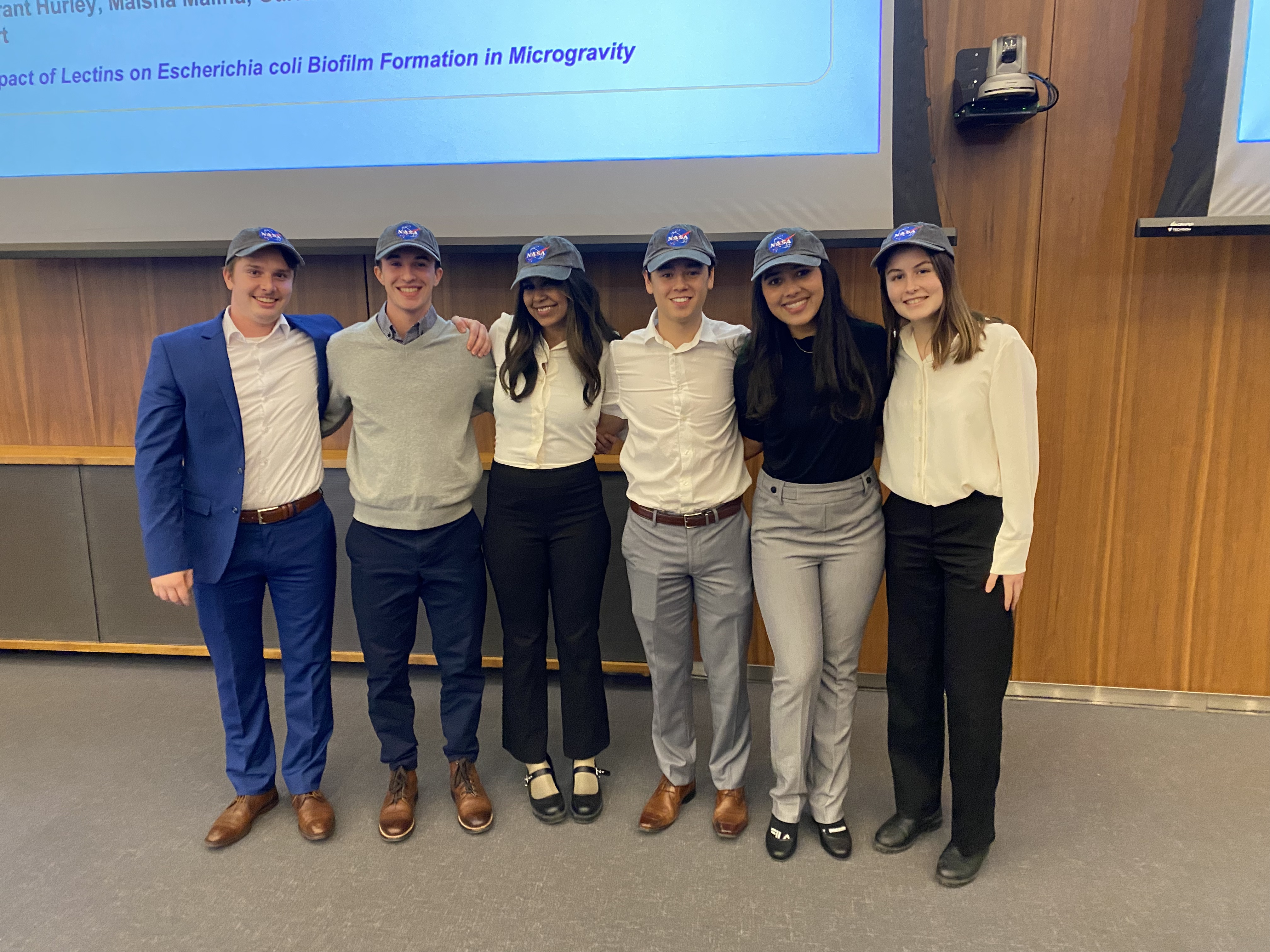 Grant Hurley, Maisha Maliha, Gurleen Multani, Cole Monro, Tessa Murchison, & Ryan Stewart stand together wearing NASA branded baseball hats