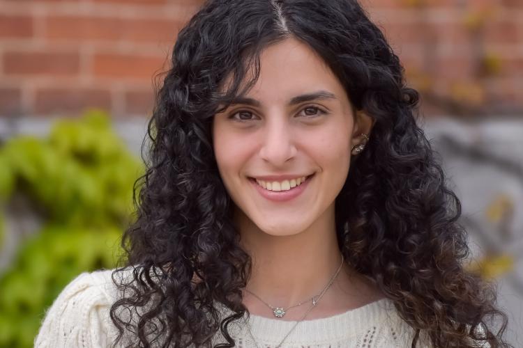 Headshot of Zahraa Abdul Hasan in front of a background of blurred out red brick.