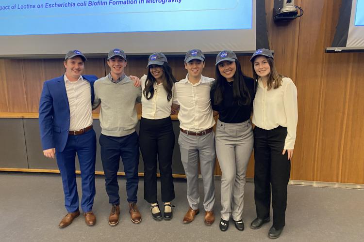 Grant Hurley, Maisha Maliha, Gurleen Multani, Cole Monro, Tessa Murchison, & Ryan Stewart stand together wearing NASA branded baseball hats