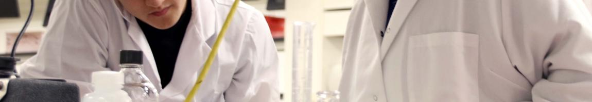 Two students in lab coats working in a laboratory