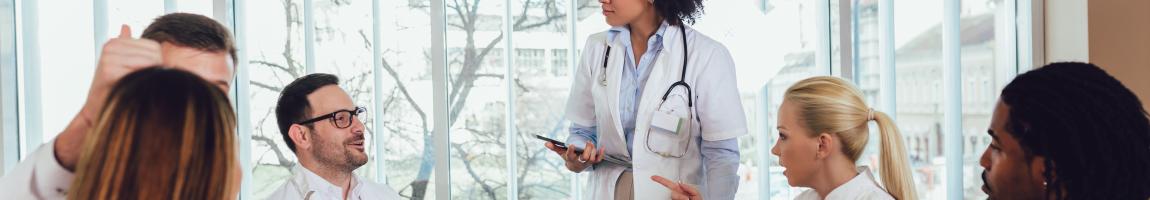 A group of medical professionals have a discussion while sitting around an office table.
